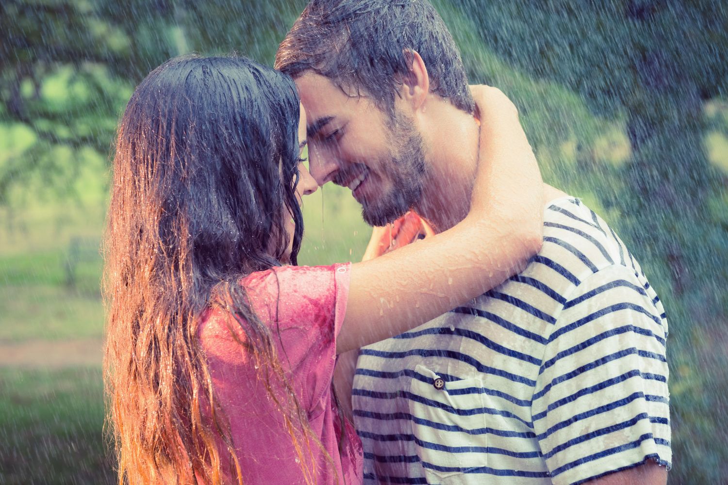 Romantic couple embracing in the rain about to kiss