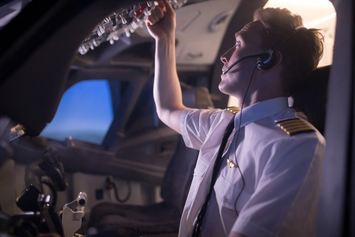 Pilot preparing flight instruments in cockpit.