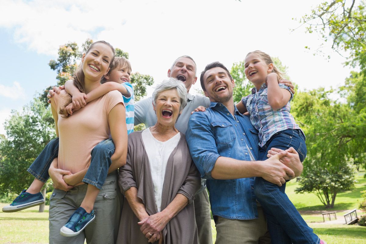 Parents hugging children family portrait in park.