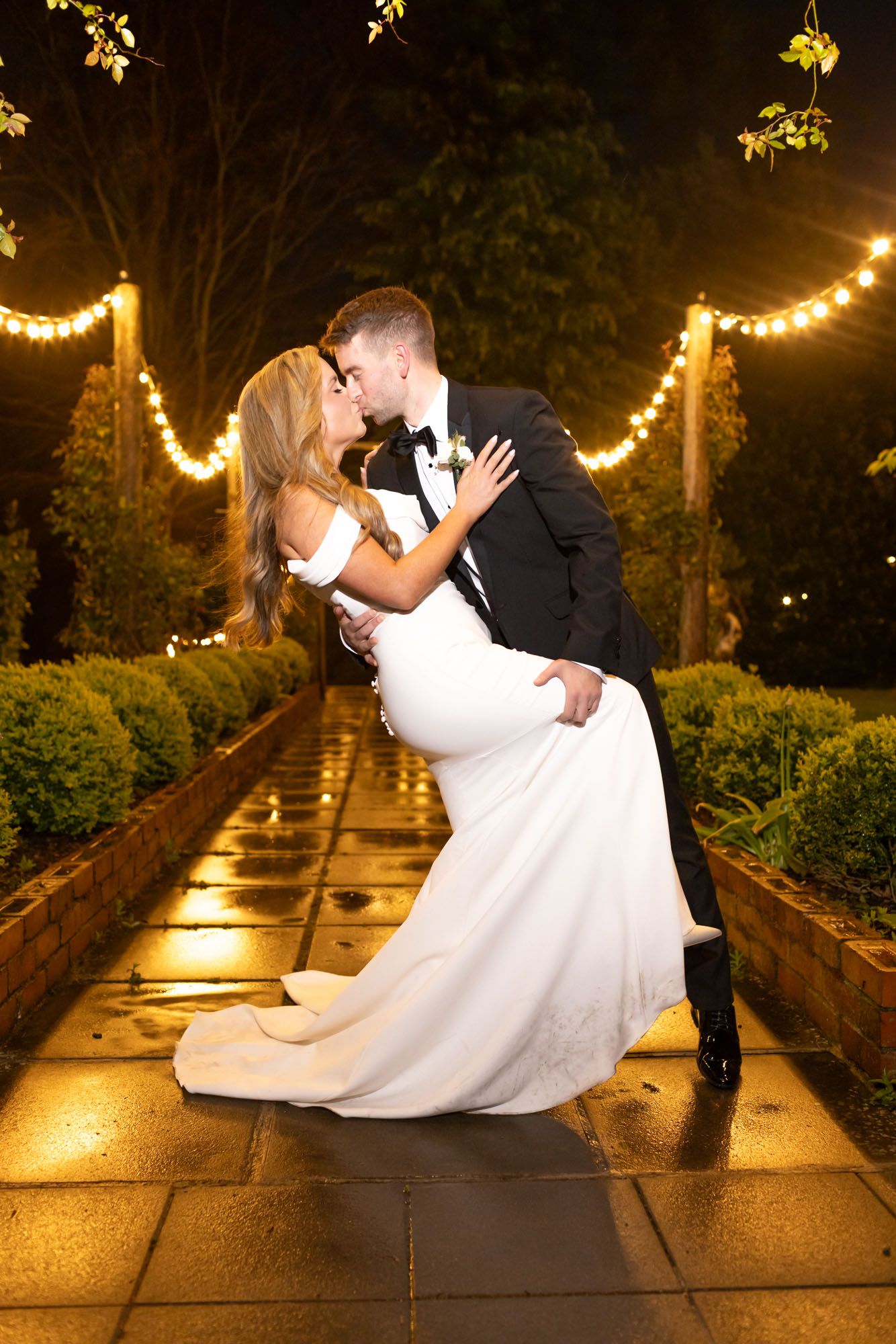 Bride and groom kissing outdoors at night during wedding photoshoot.