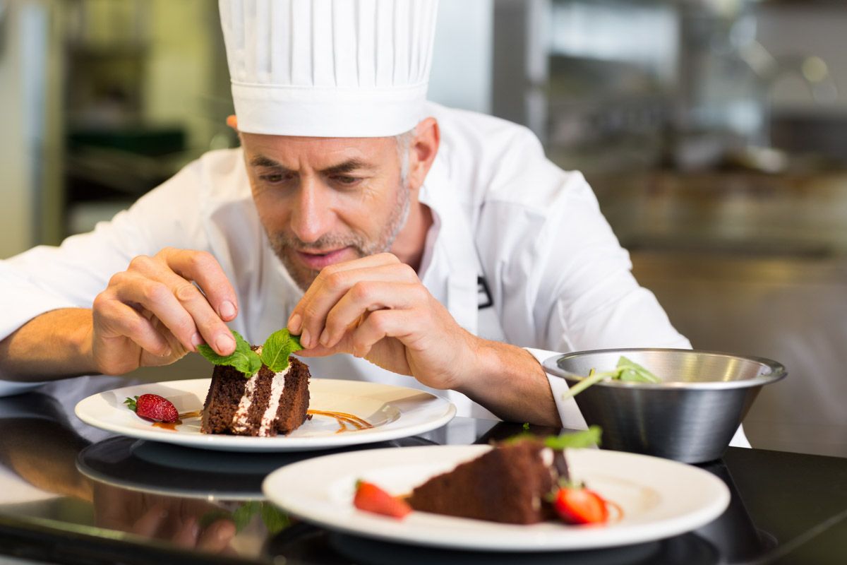 Head chef adding final touches to gourmet meal.