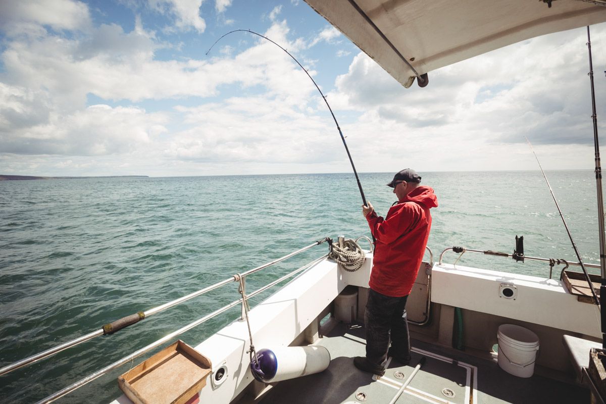 Fisherman of the coast of Cork holding fishing rod while standing on boat.