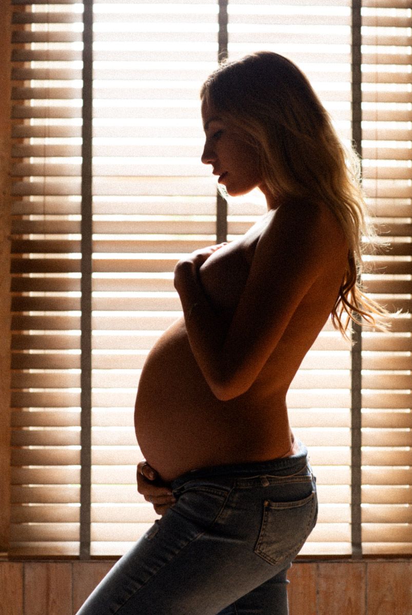 Beautiful photo of an expecting mother showing her baby bump in natural light