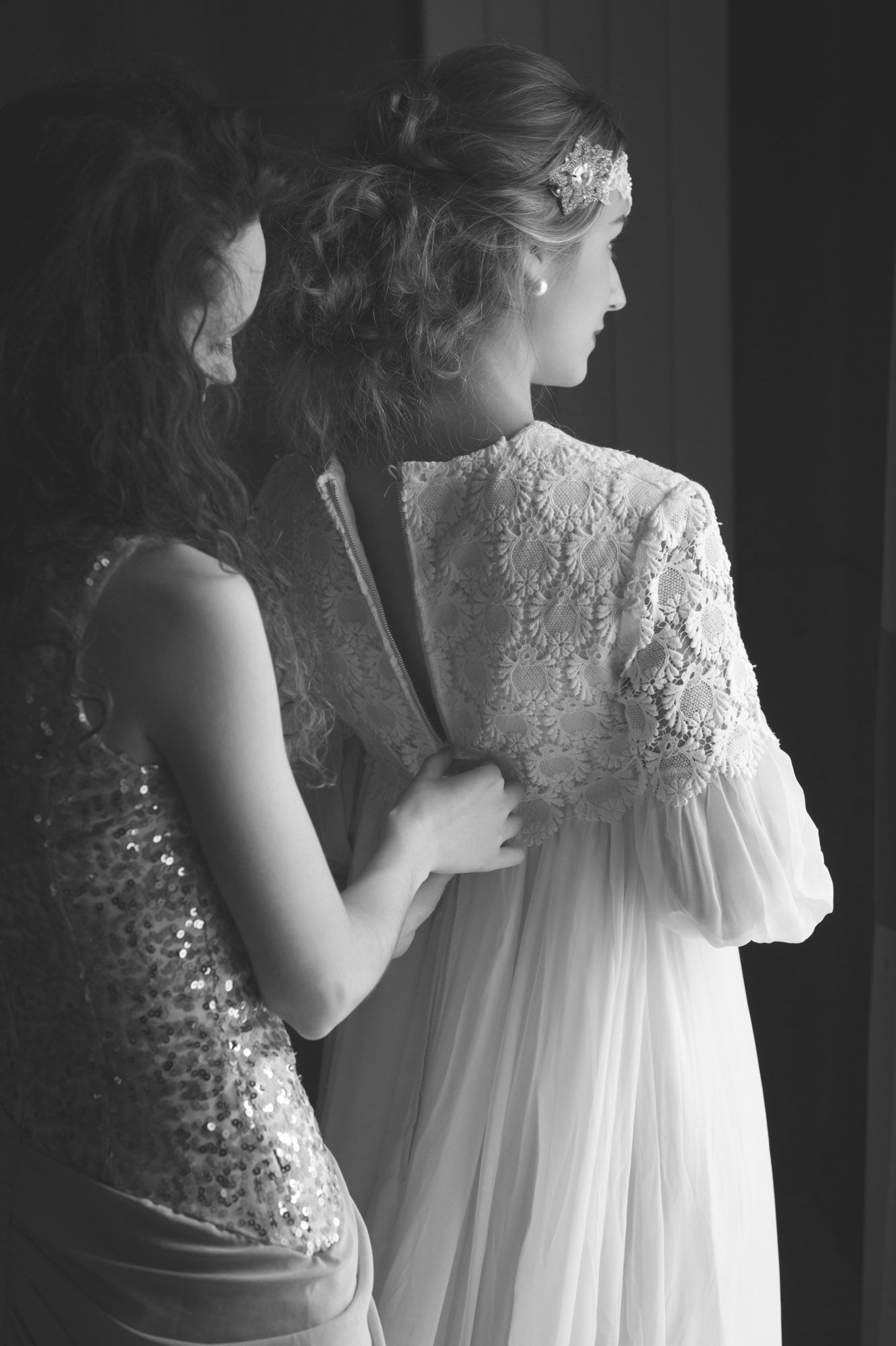 Bridesmaid helping Bride with her dress before wedding.