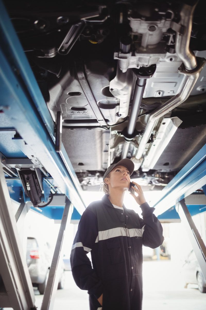 Mechanic inspecting under lifted vehicle in Cork workshop.
