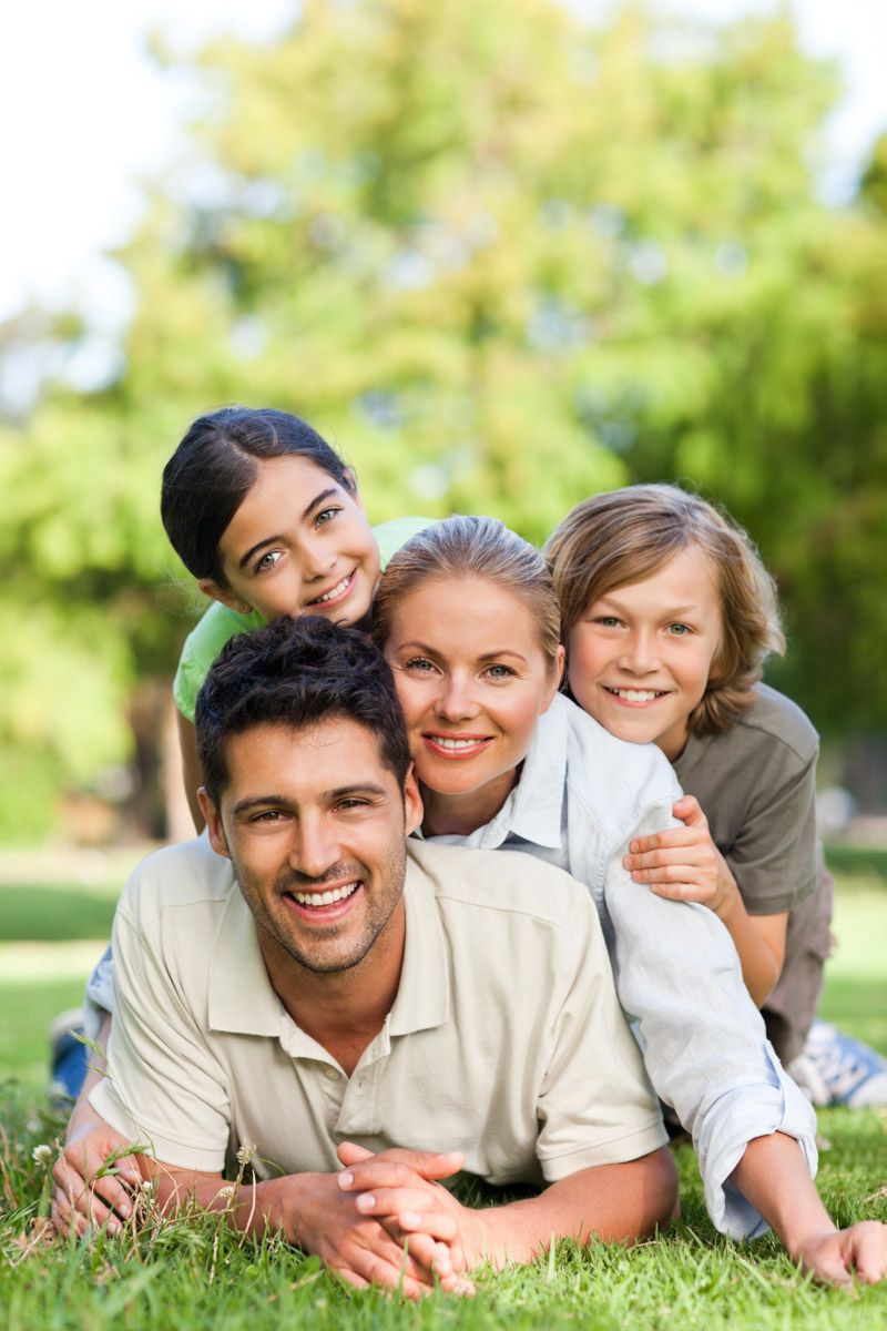Family of four smiling portrait lying in garden.