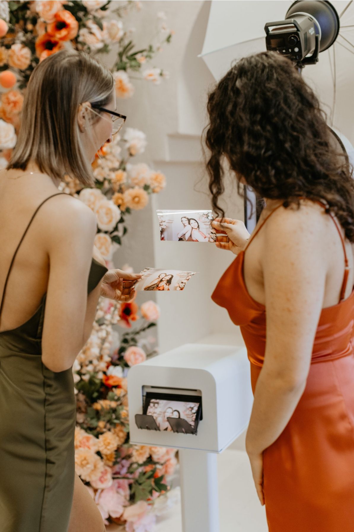 A series of candid moments as bridesmaids in coral and olive dresses look at photos during a wedding celebration.
