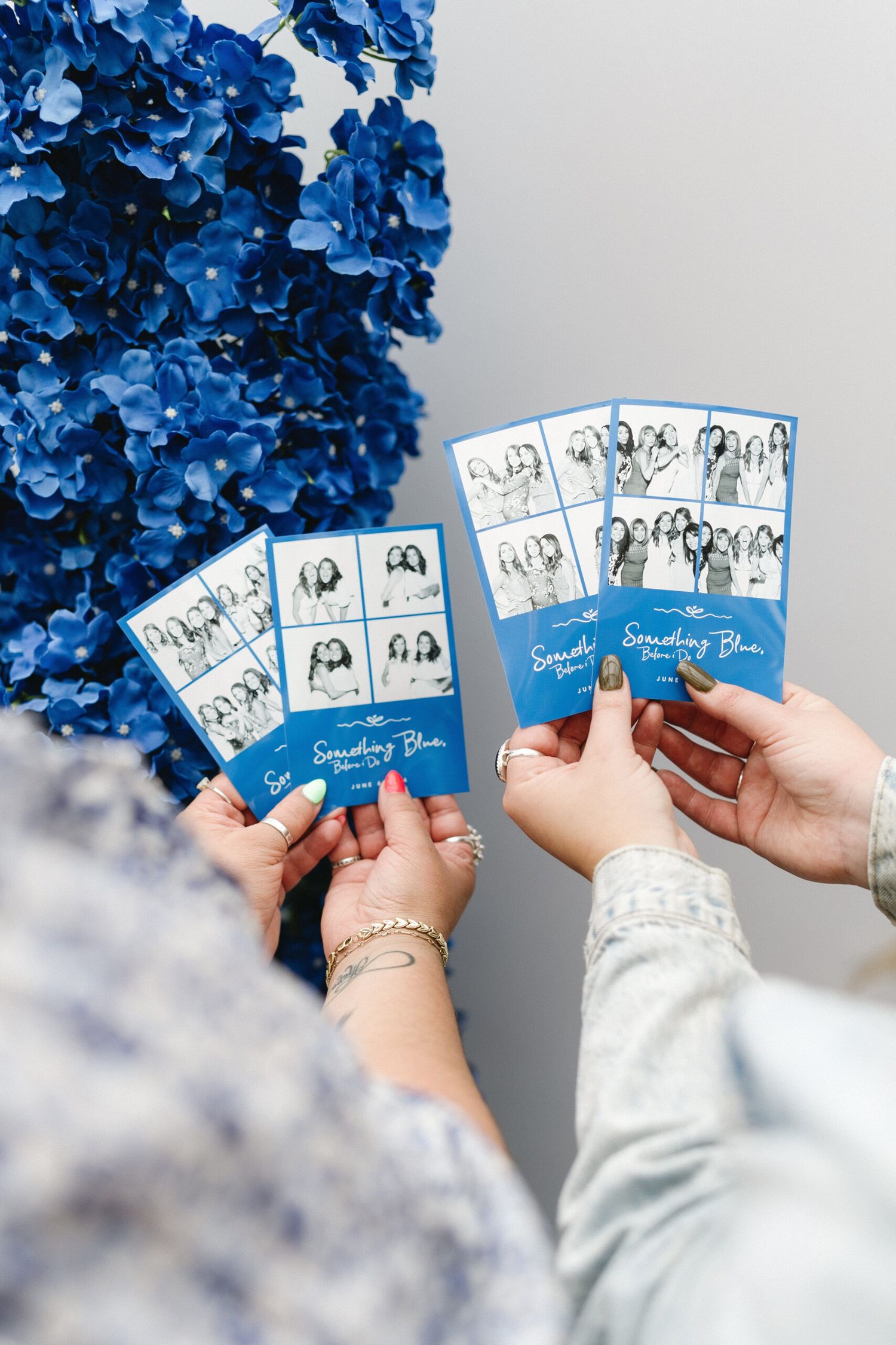 Hands holding blue photo cards with floral arrangements in the background.