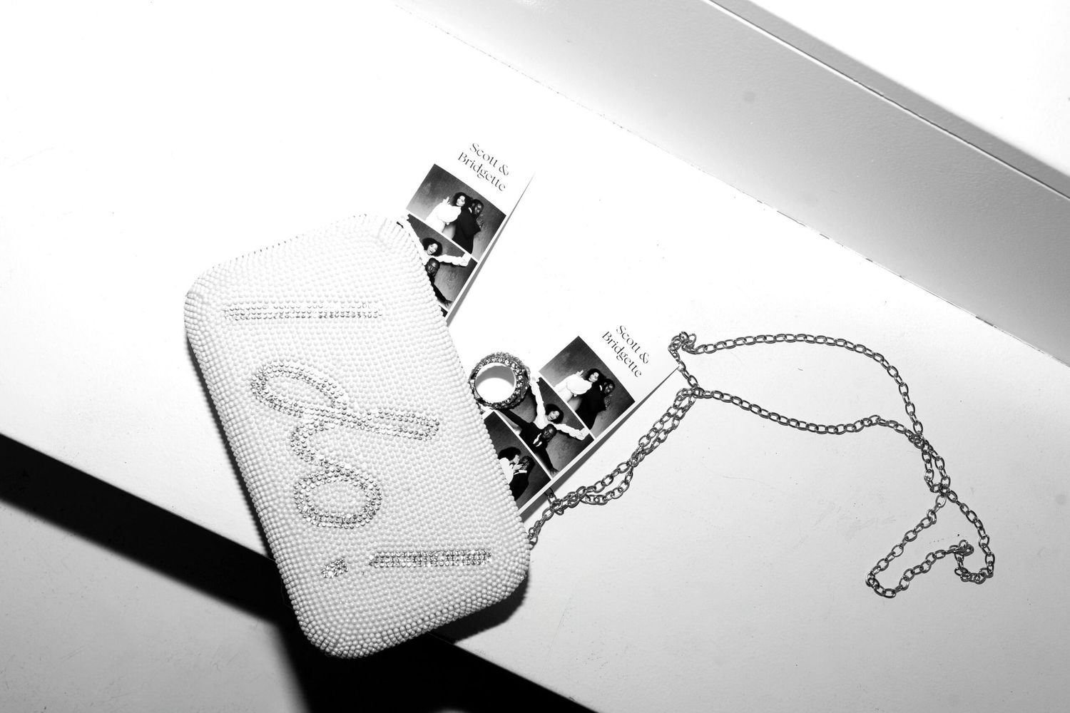 Monochrome image of sparkly evening bag with photo strips and chain detail.