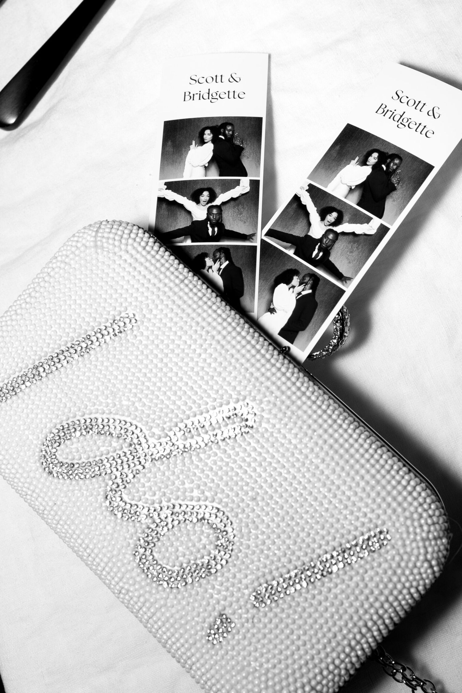 Black and white photo strips and sparkly clutch bag arranged on white surface.