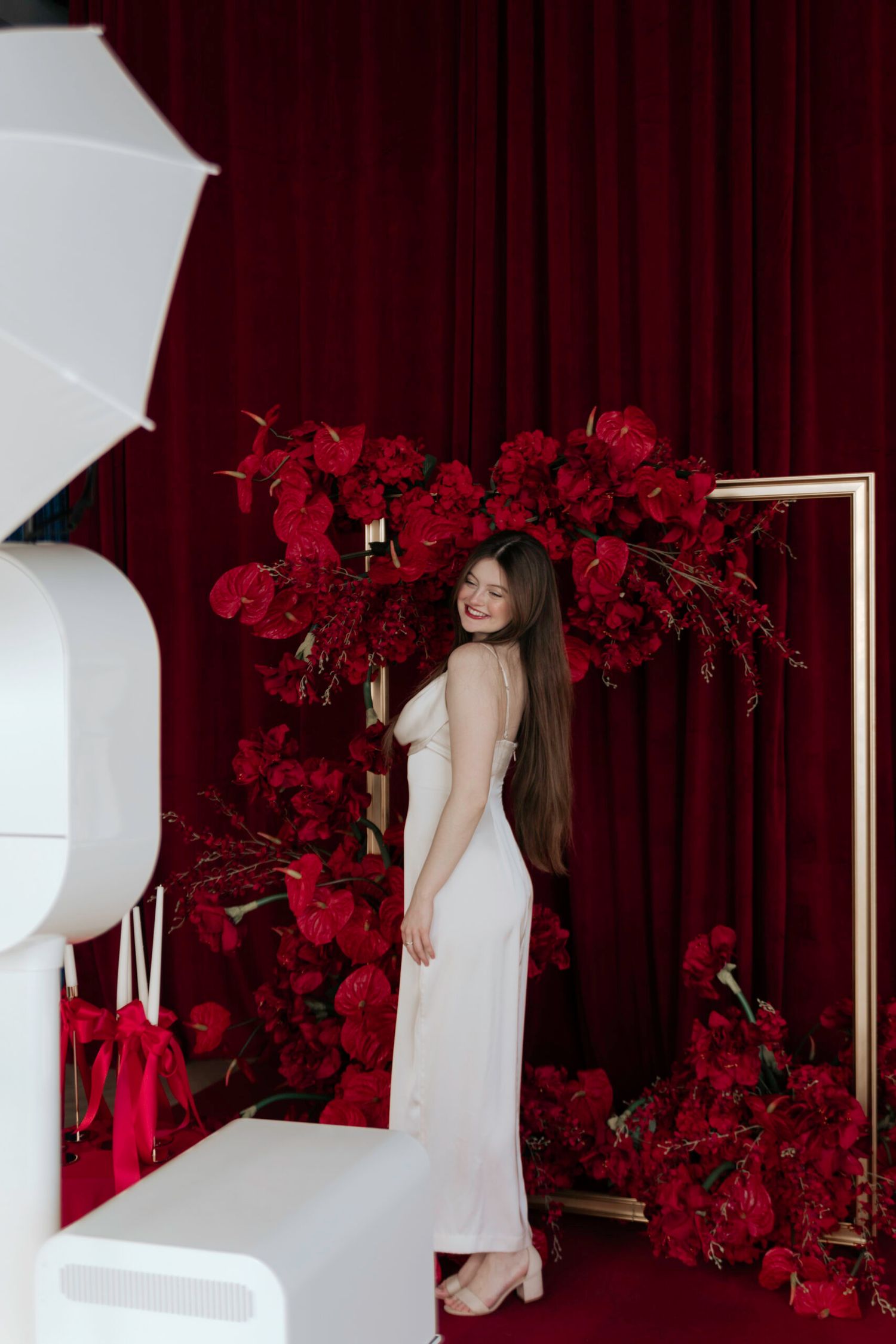 Elegant photo shoot setup with white geometric props and deep red floral decorations.