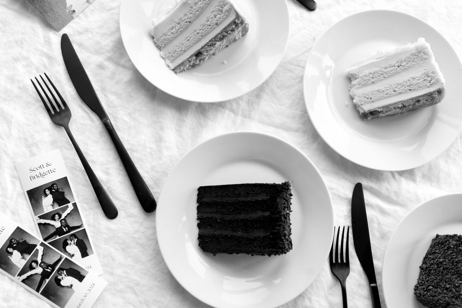 Black and white overhead view of cake slices and table settings with plates and utensils.