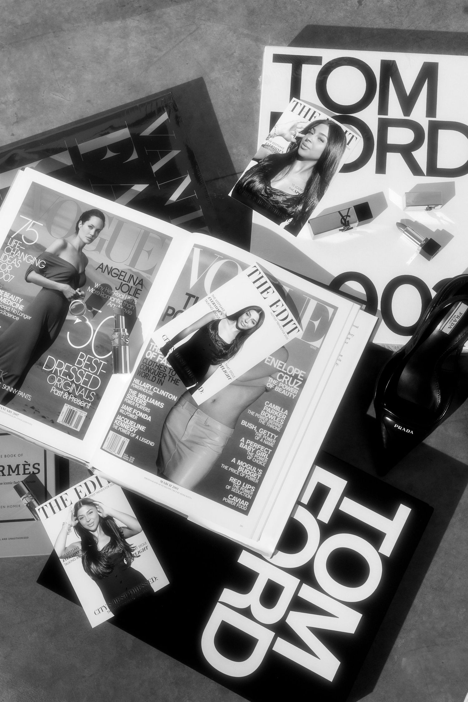 Black and white editorial magazine pages spread across a flat surface showing fashion and typography layouts.