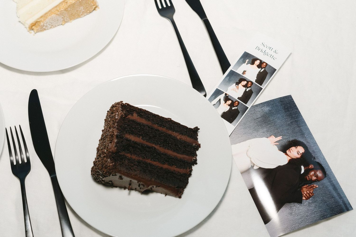 Elegant place setting with chocolate cake slice and cutlery on white plates.