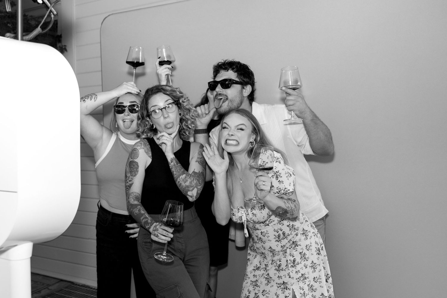 Four black and white candid photos showing people smiling and laughing together at a social gathering.
