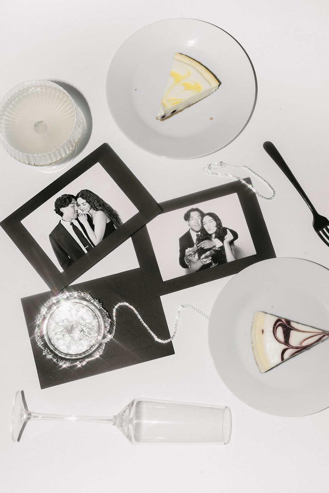 Wedding reception details with photo strips, cake slices and empty wine glass on white background.