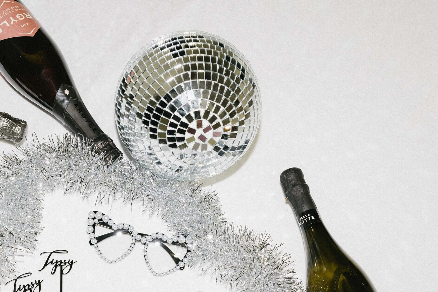 Festive party setup with disco ball, champagne bottles, and decorative silver tinsel.