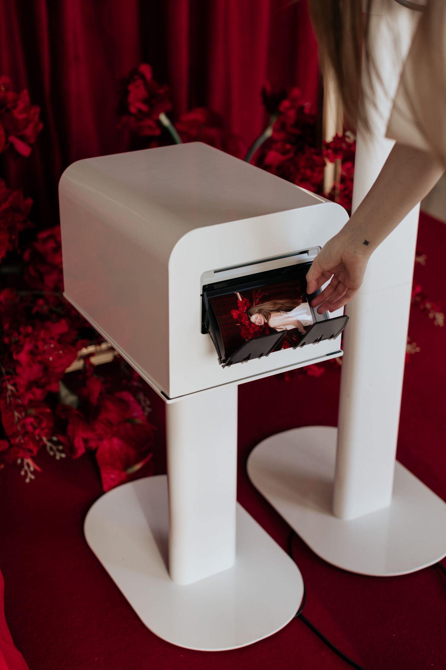White geometric photo booth setup against a red curtain backdrop.
