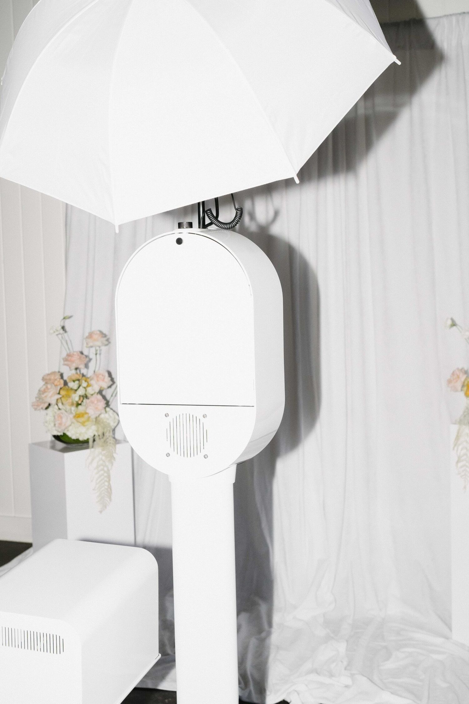 White paper lantern lamp shades hanging in sequence against a light colored wall with floral decorative elements.