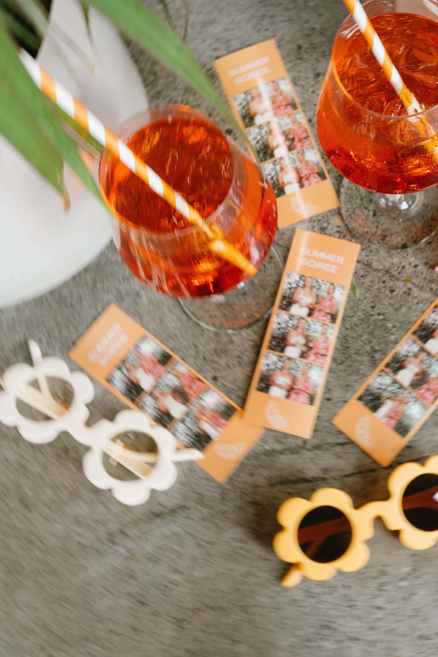 Orange cocktails and decorative photo cards arranged on textured gray surface.