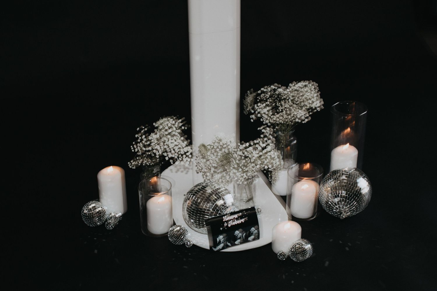 Atmospheric display of white candles and silver decorations in low light setting.