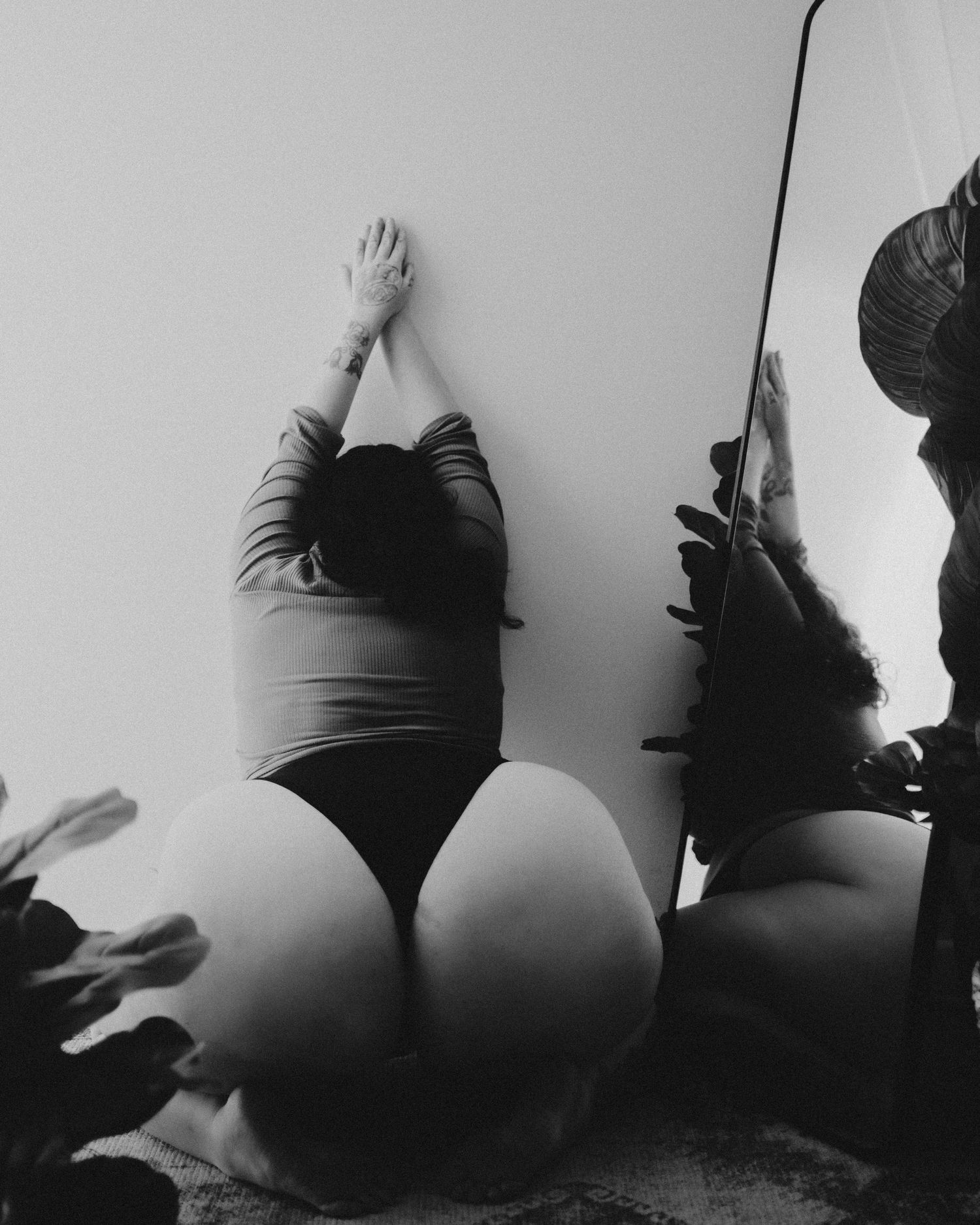 A black and white artistic photograph showing stretching silhouettes against a plain wall.