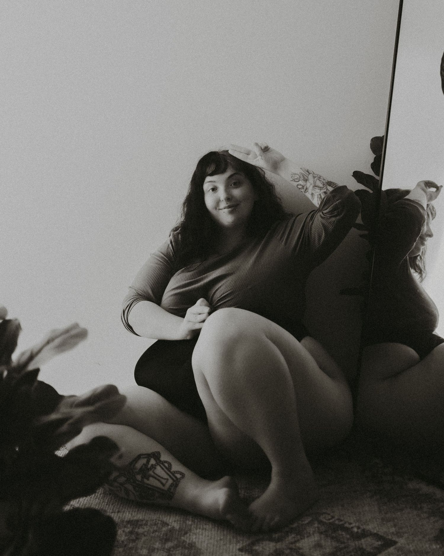 Black and white photograph of a person in dark clothing lounging on a floor in an artistic pose.