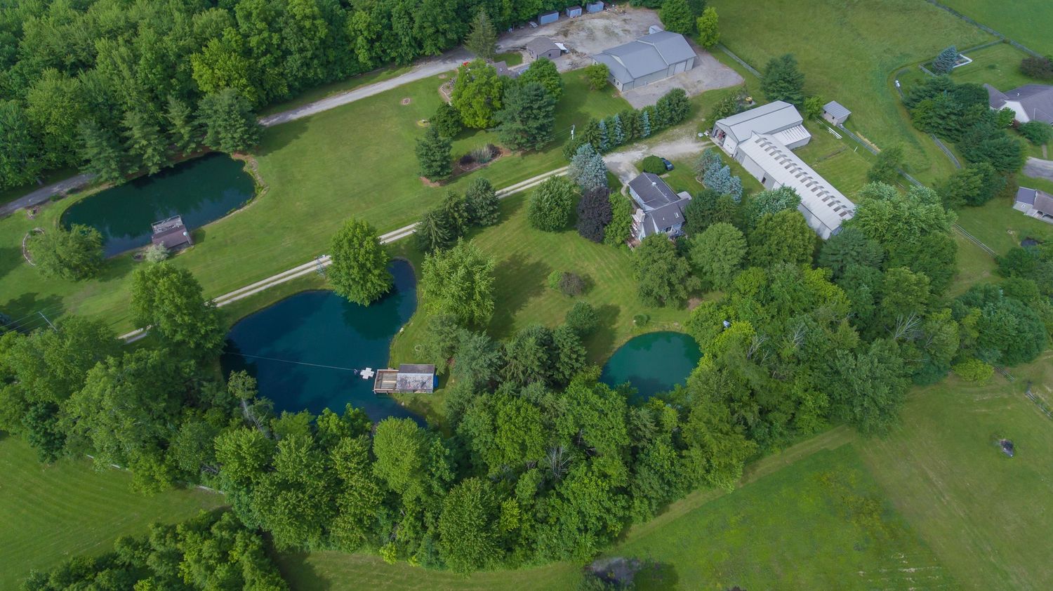 Overhead view of farmland property with open fields and water feature