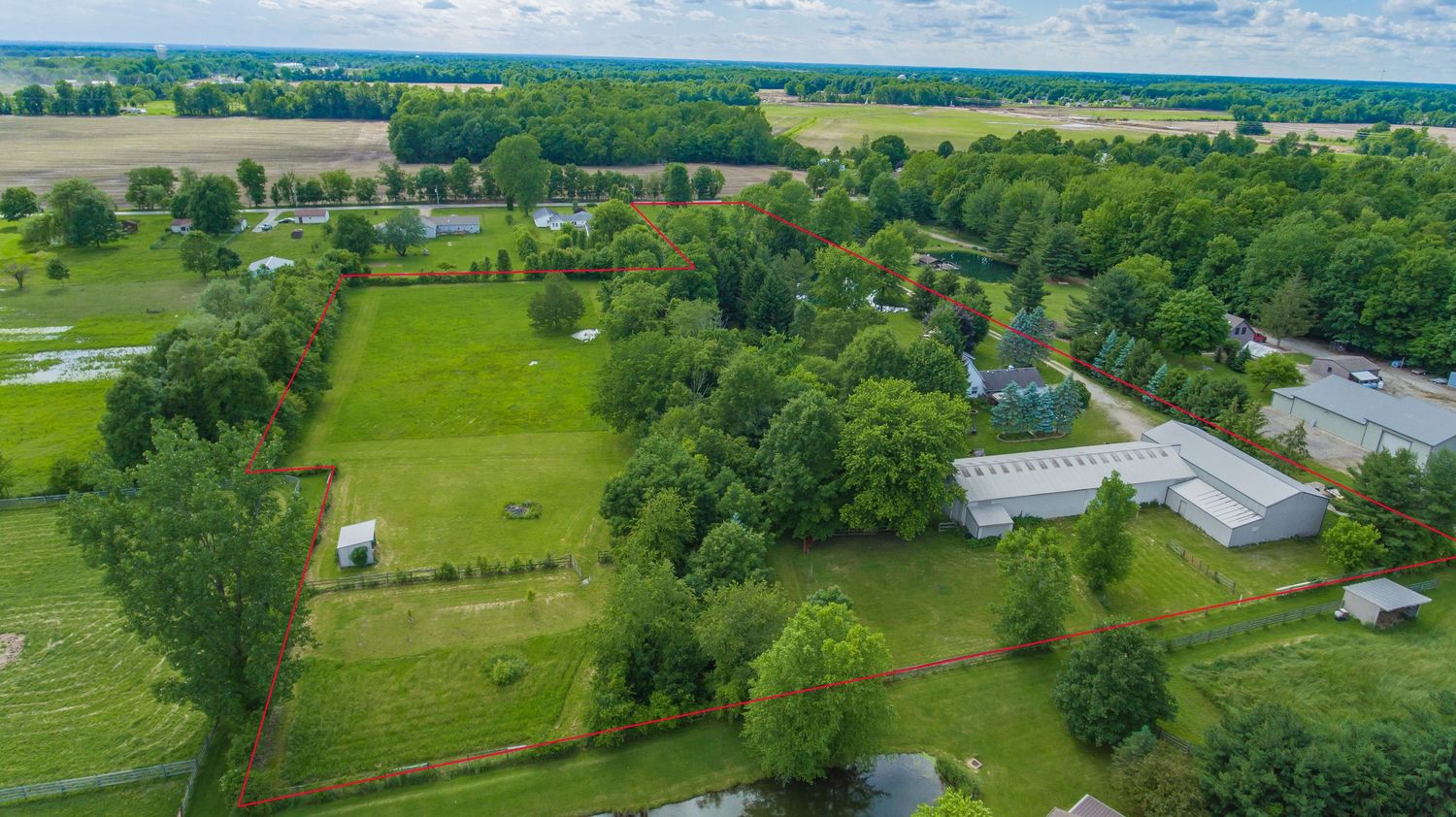 Aerial drone photo of large rural property with pond and pasture