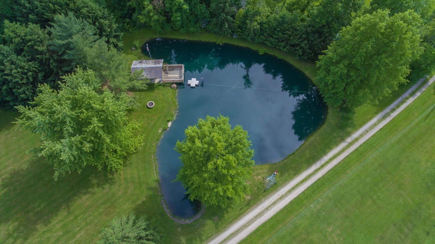 Drone view of rural Central Ohio estate featuring open fields, trees, and private pond