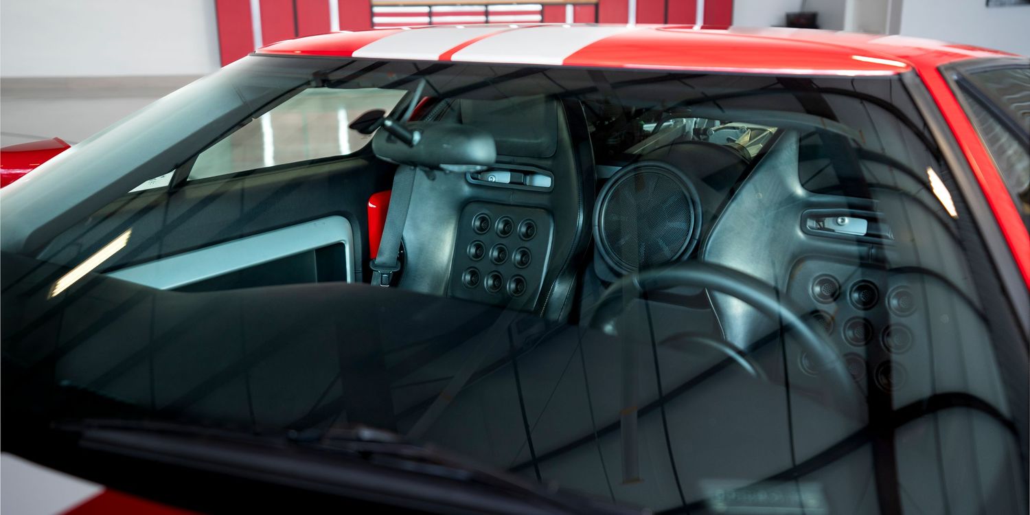 Side window and roofline details of red sports car in showroom lighting.