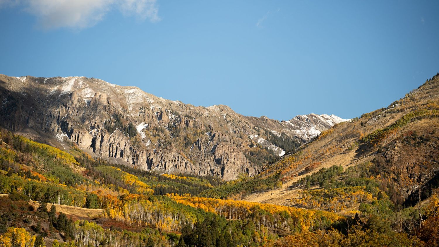 Panoramic view of rugged mountain peaks with autumn colors in the foreground.