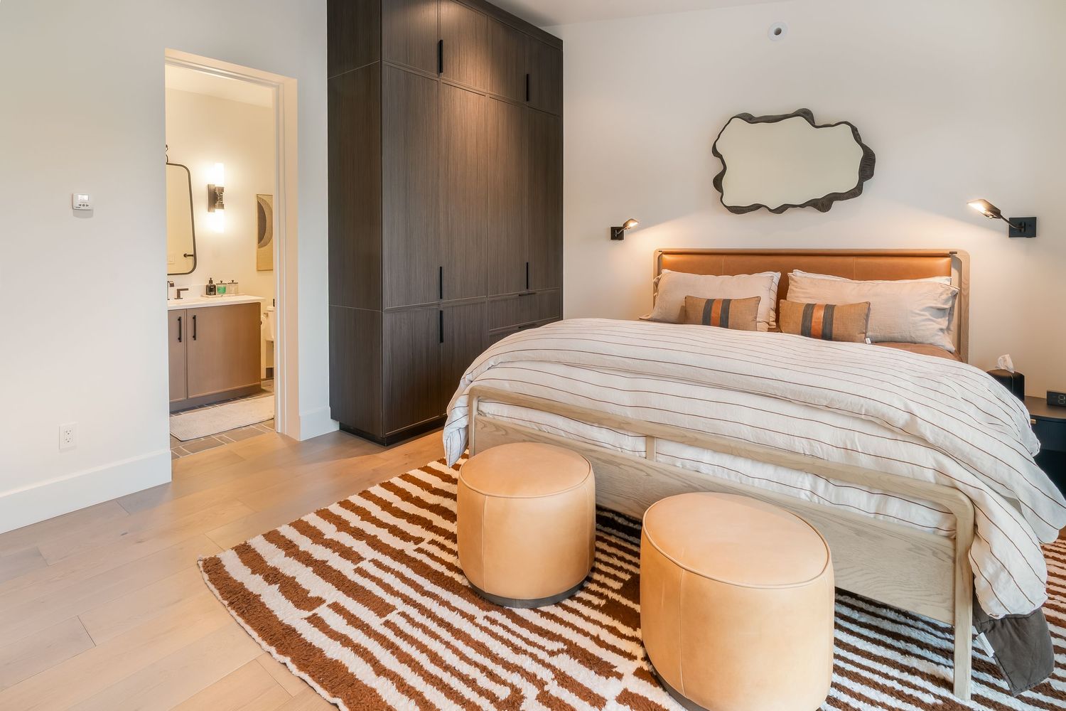 Contemporary bedroom design featuring neutral colors, wall sconces, and geometric patterns.