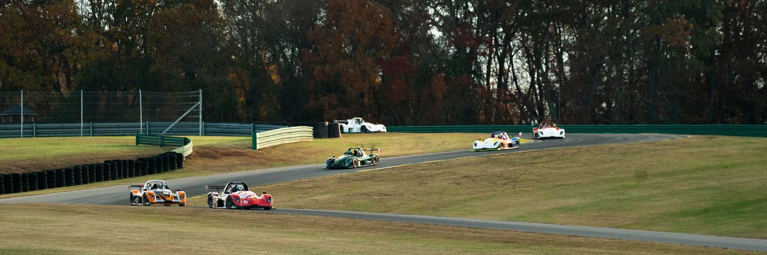 Wide view of a racing circuit with cars on track during competition.
