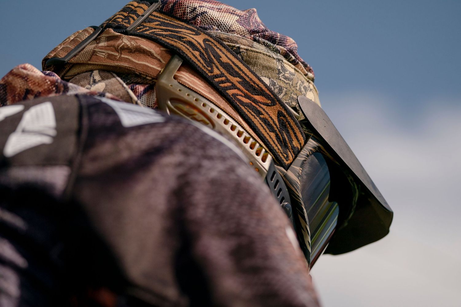 Close-up of ornate paintball mask and gear from low angle.