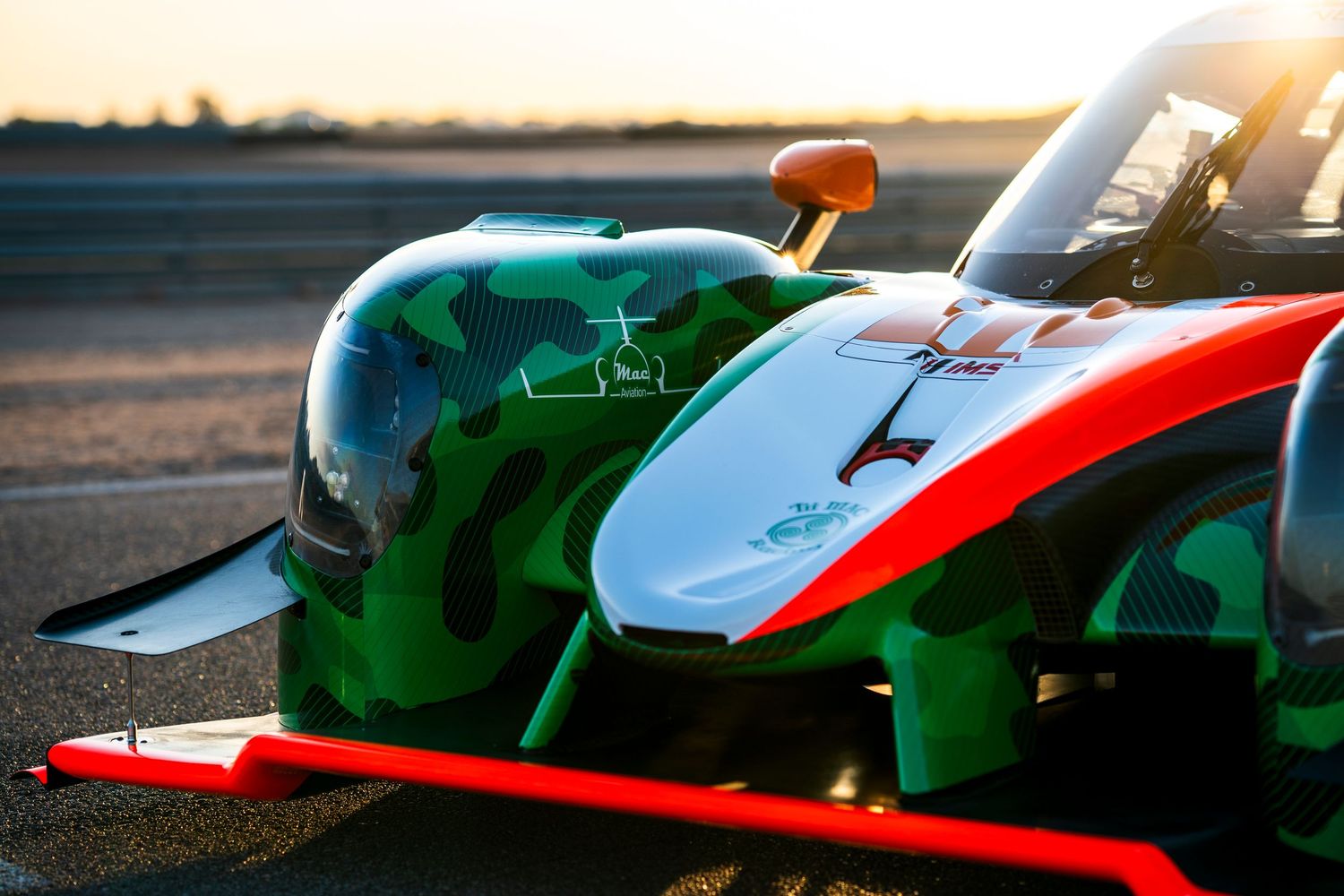 Multiple race cars showcasing colorful liveries and aerodynamic designs at sunset.