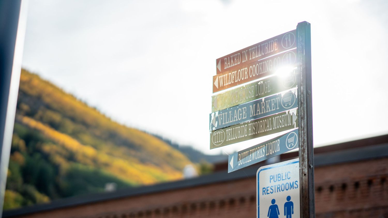 Directional signpost against mountain backdrop with fall colors.