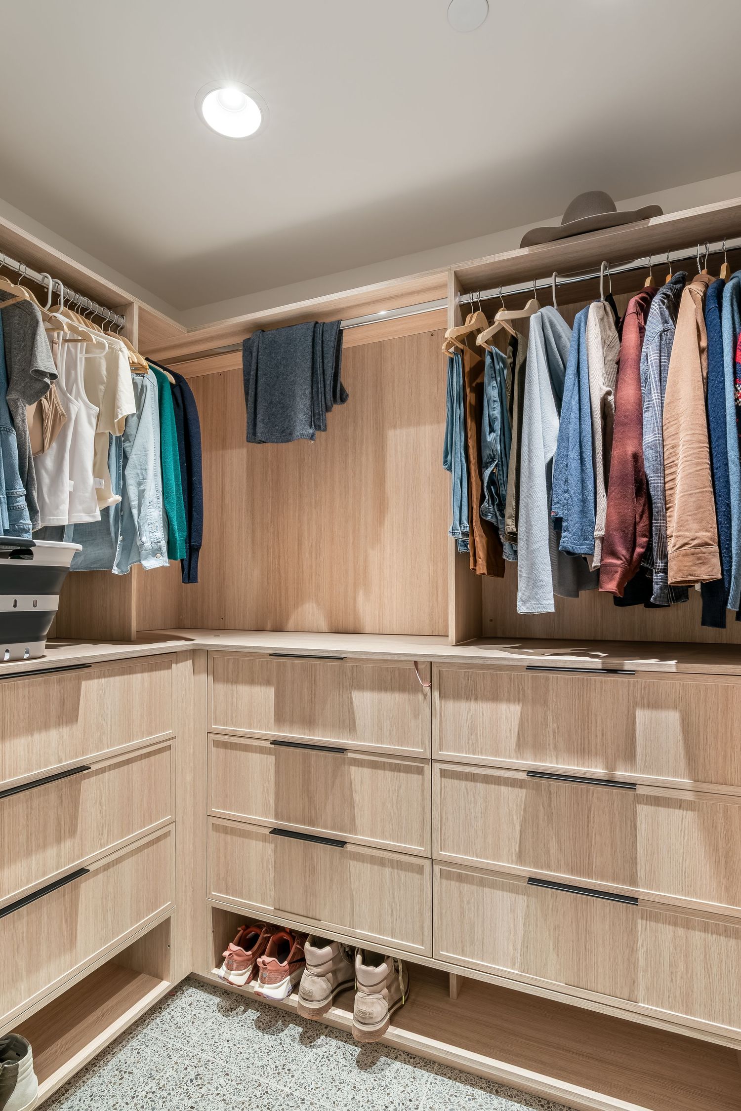 Spacious walk-in closet with light wood finishes and extensive hanging storage for clothing and accessories.