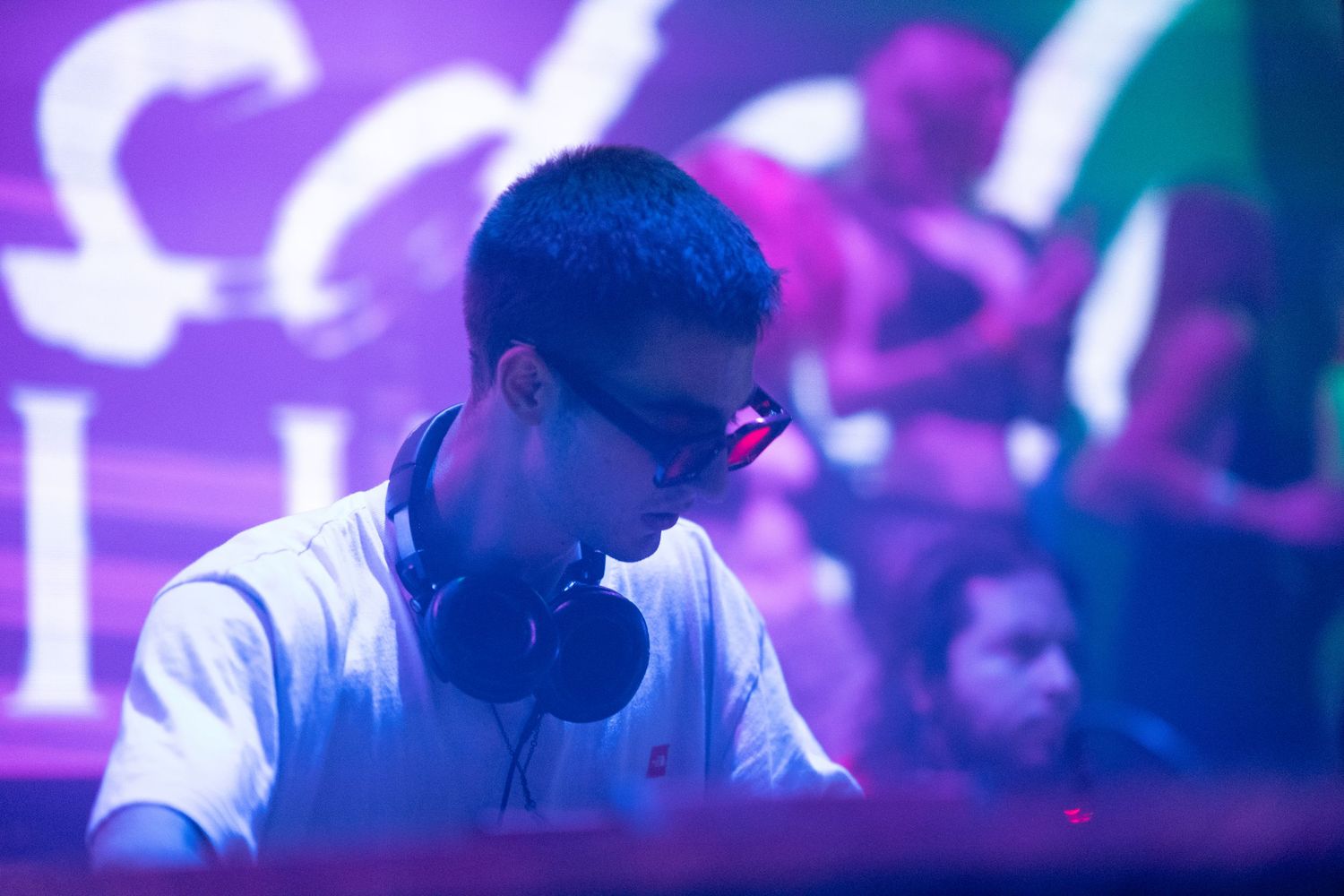 People dance and enjoy themselves at a nightclub with vibrant purple lighting and energetic atmosphere.