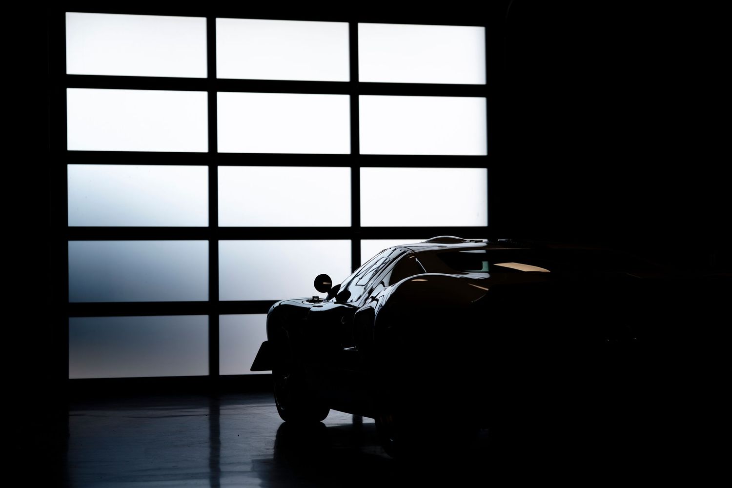 Silhouette of a grand piano against a window with horizontal blinds creating dramatic lighting and shadows.