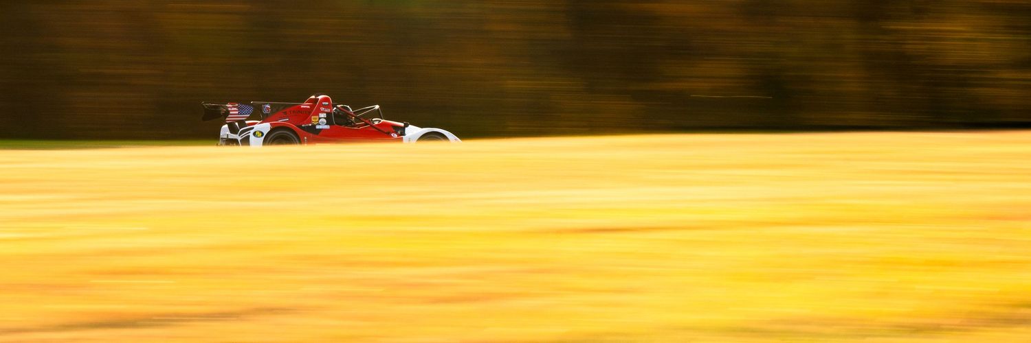 Racing car speeding along a sunlit track during golden hour.