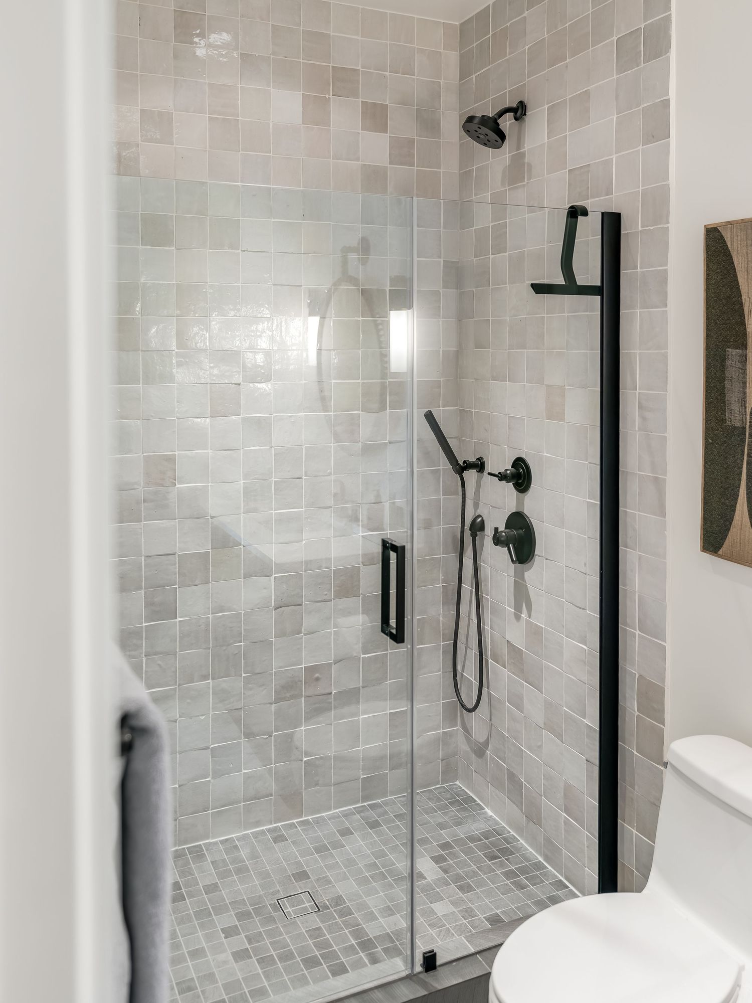 Modern bathroom interior with gray tile walls and black fixtures showcasing a sleek walk-in shower design.