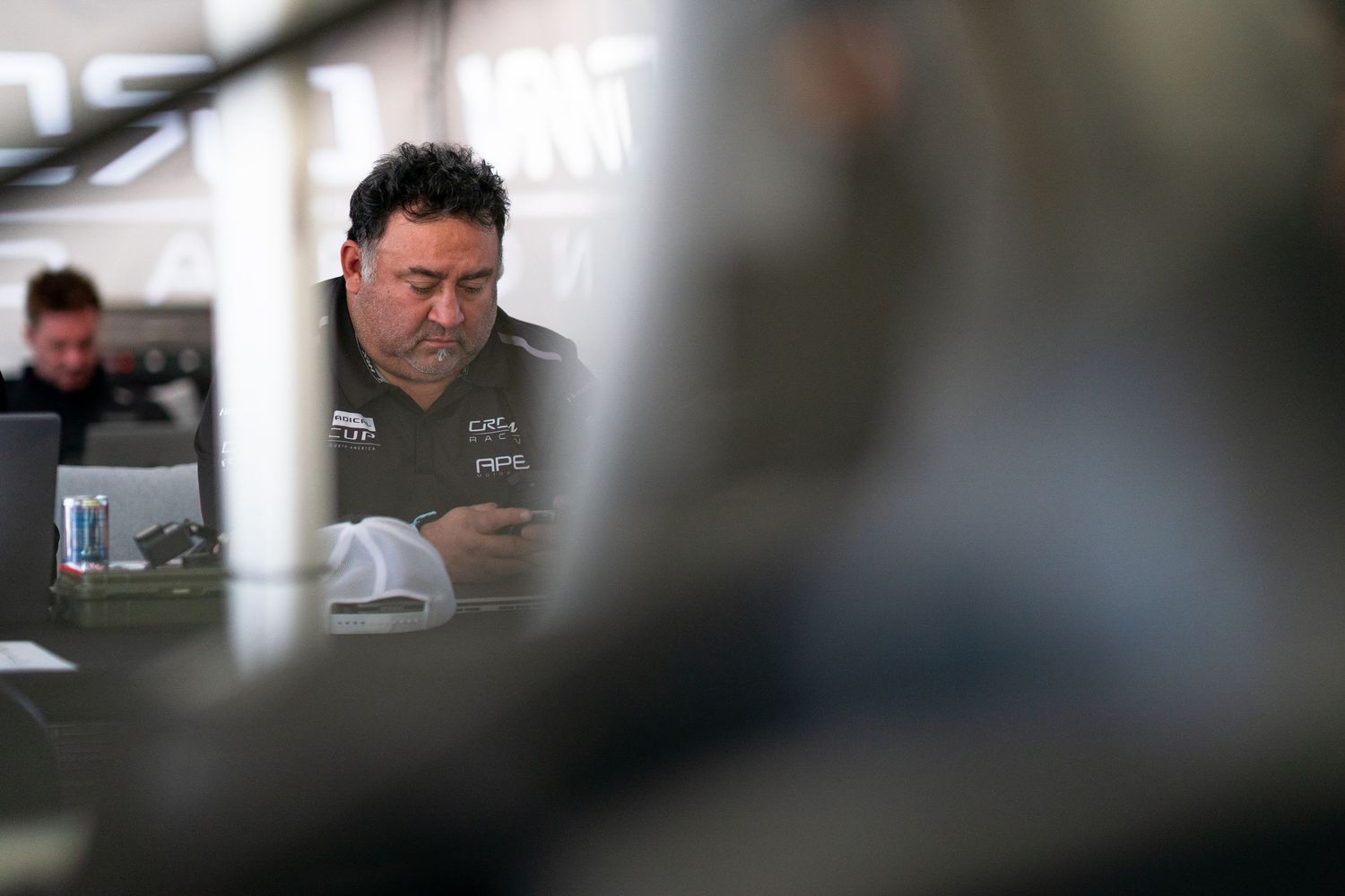 Racing team personnel focused on vehicle preparation in the garage bay.