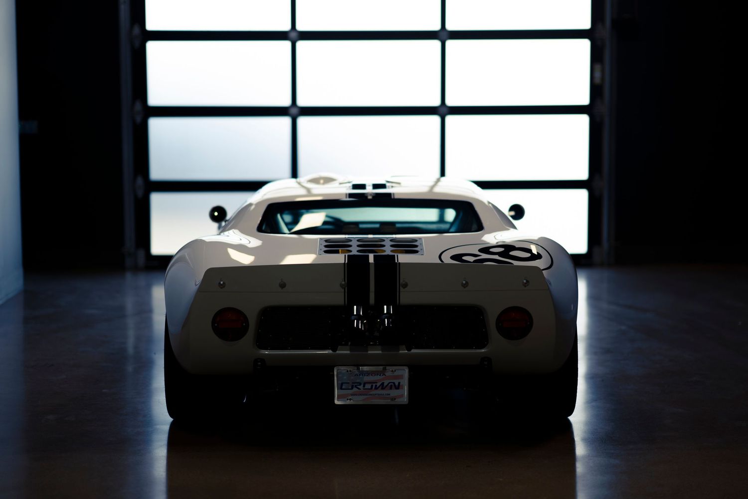 A row of classic Chevrolet Corvettes on display in a dimly lit showroom with dramatic lighting.