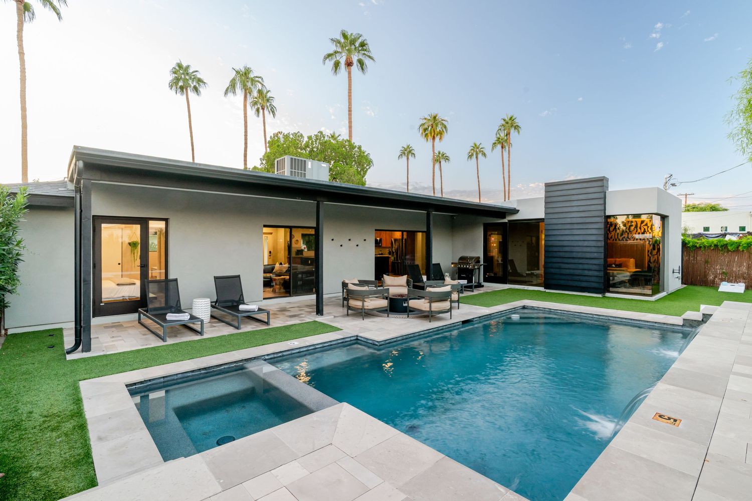 Modern backyard with sleek rectangular pool, lounge chairs, and palm trees creating a luxurious outdoor living space.