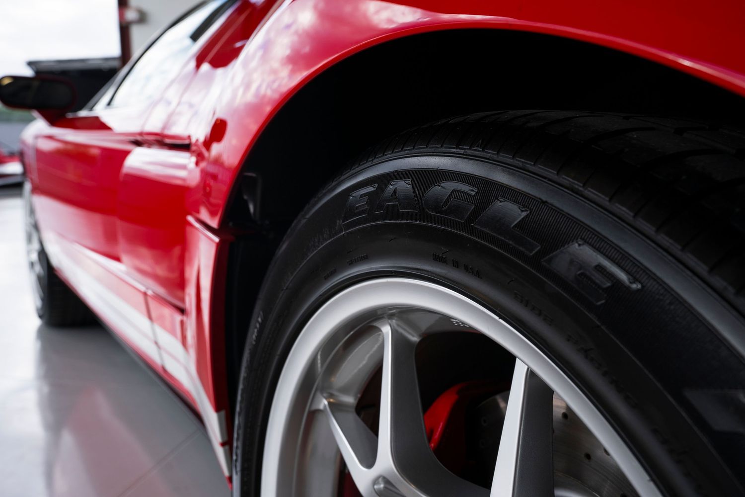 Close-up of a sports car wheel with red body panel and silver alloy rim.