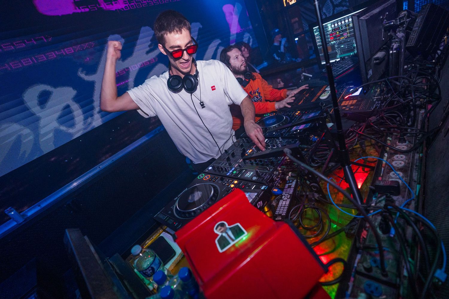 A series of silhouettes performing at a nightclub with colorful purple and blue lighting effects in the background.