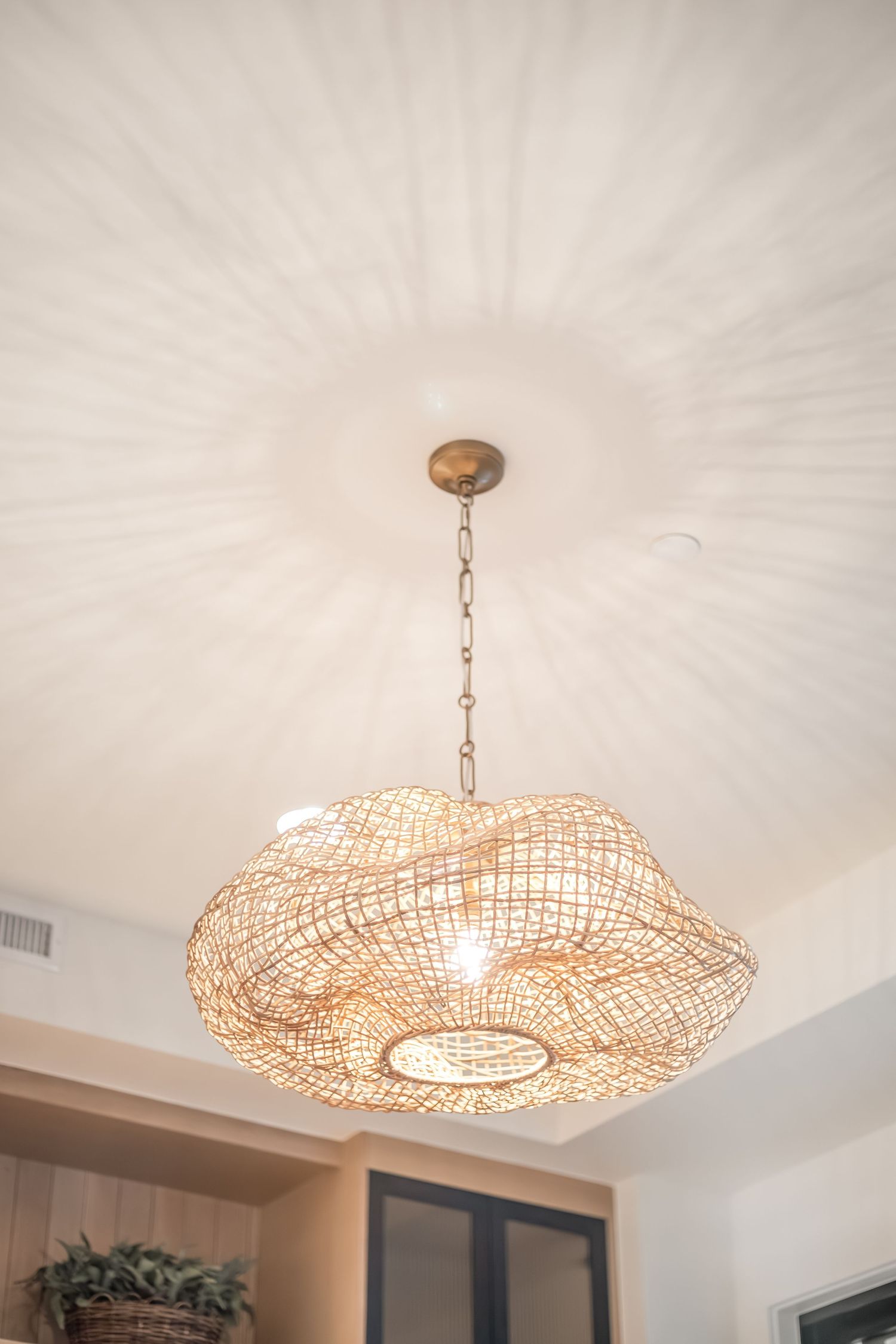 A series of modern woven rattan pendant lights hanging from a white ceiling create an elegant lighting arrangement.