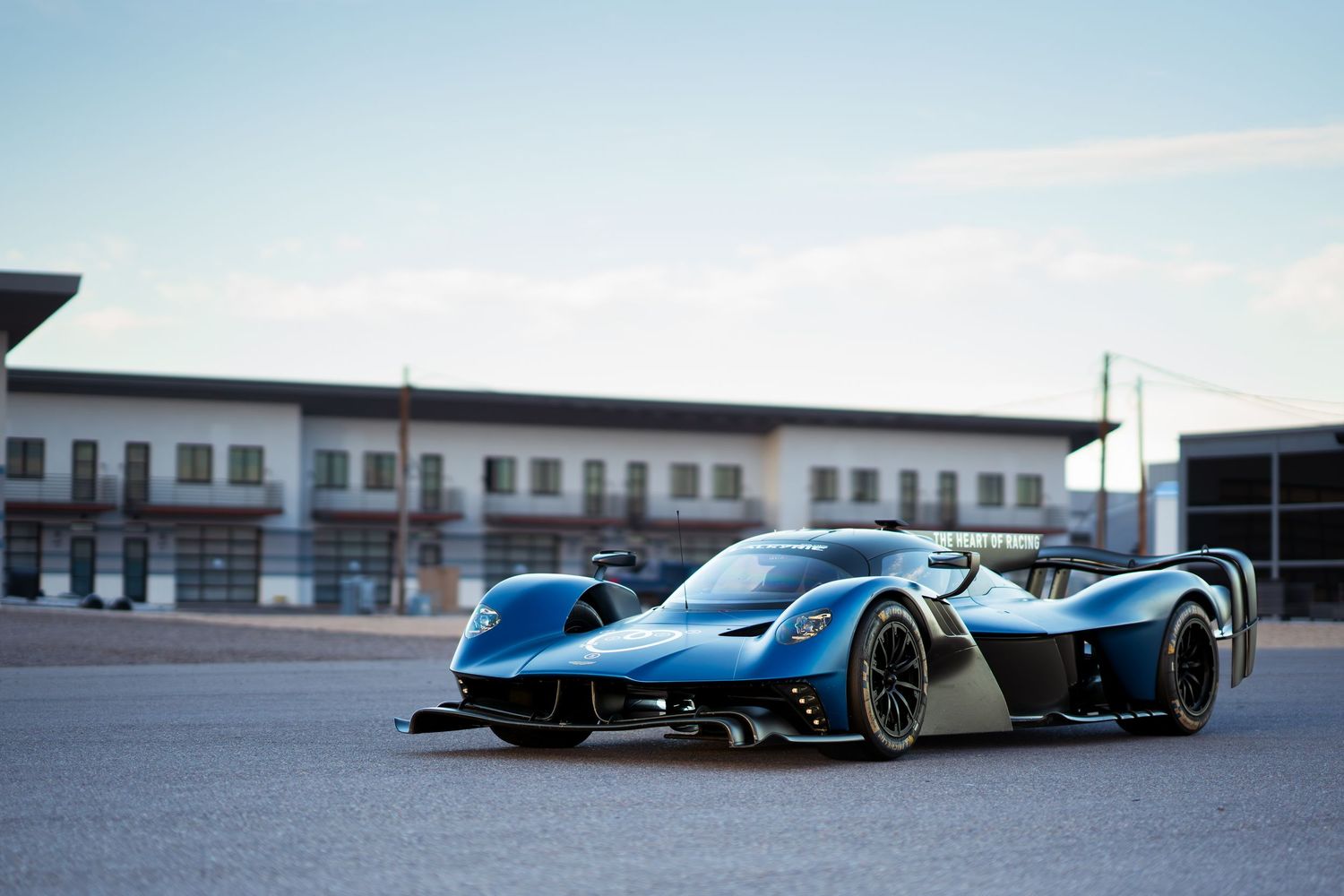 Sleek blue Formula E electric race car on display at a racing facility with buildings in the background.