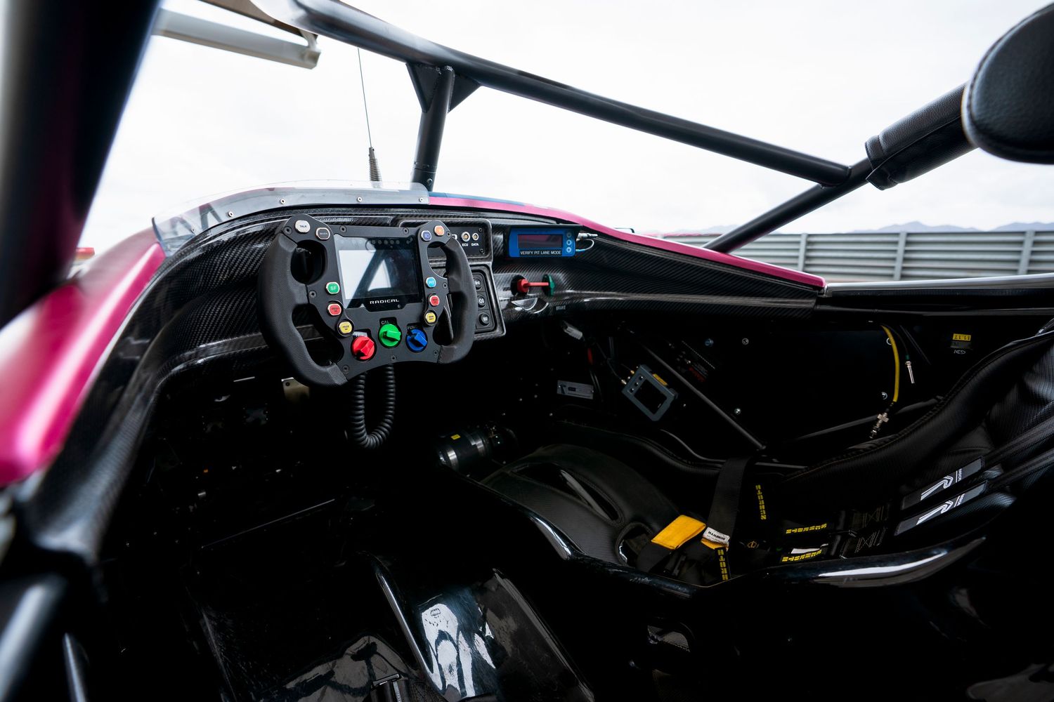 Interior cockpit view of a modern racing car showing the steering wheel and digital dashboard.